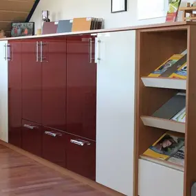 Moderner Aktenschrank mit glänzenden Türen und offenem Regal für Büroorganisation.