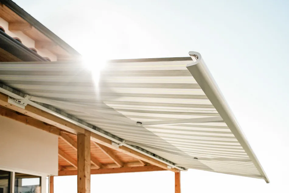 Moderne Markise als Sonnenschutz auf einer Terrasse mit Holzunterkonstruktion bei Sonnenlicht.