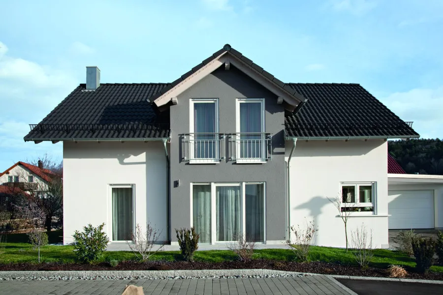 Modernes Einfamilienhaus mit Satteldach, Balkon und gepflegtem Vorgarten bei Tag.